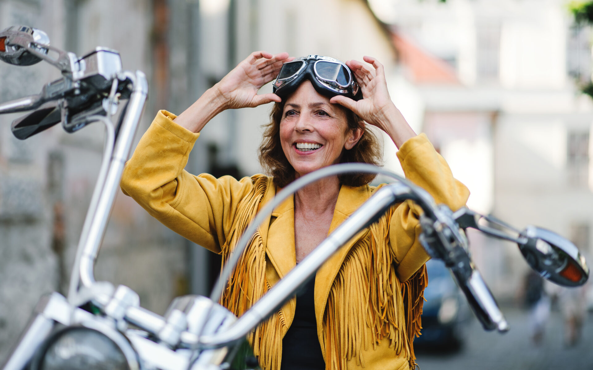 Ältere Frau sitzt lächelnd auf einem Motorrad